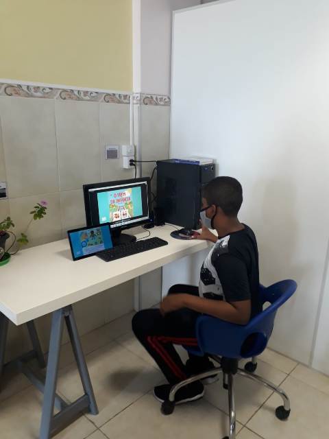 menino sentado em cadeira azul olhando para o computador