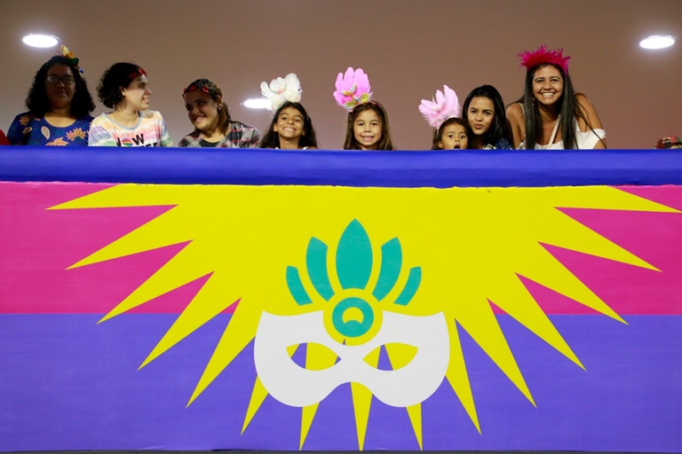 oito pessoas sorridentes assistindo desfile de escolas de samba no camarote