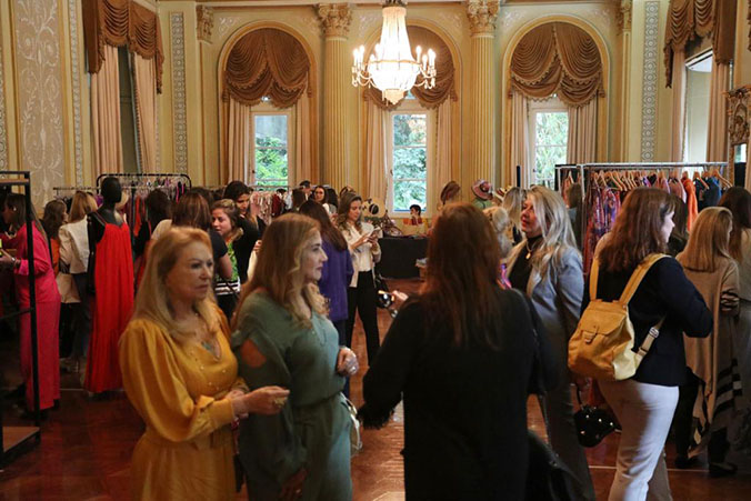 Exposição de roupas com muitas pessoas em um salão.