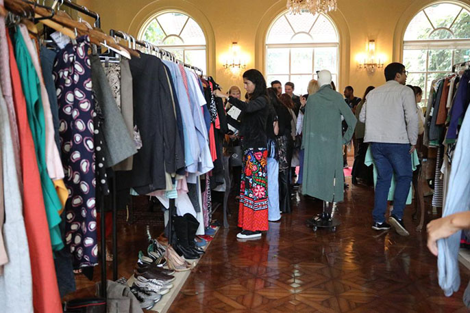 Exposição de roupas com muitas pessoas em um salão.