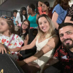 Família sentada sorrindo e assistindo uma peça teatral.