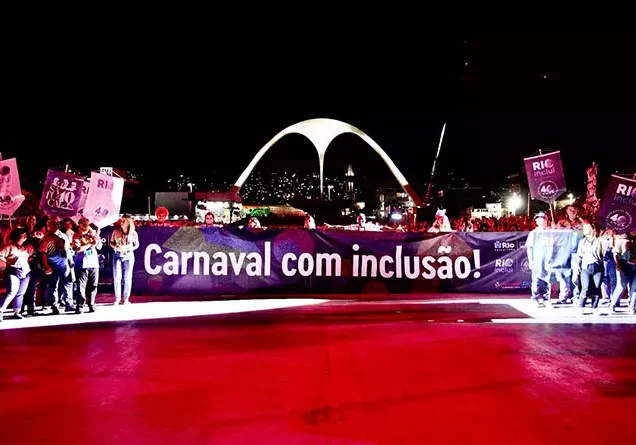 Foto dos colaboradores com a equipe técnica no evento de Carnaval de 2024, segurando a faixa "carnaval da inclusão".